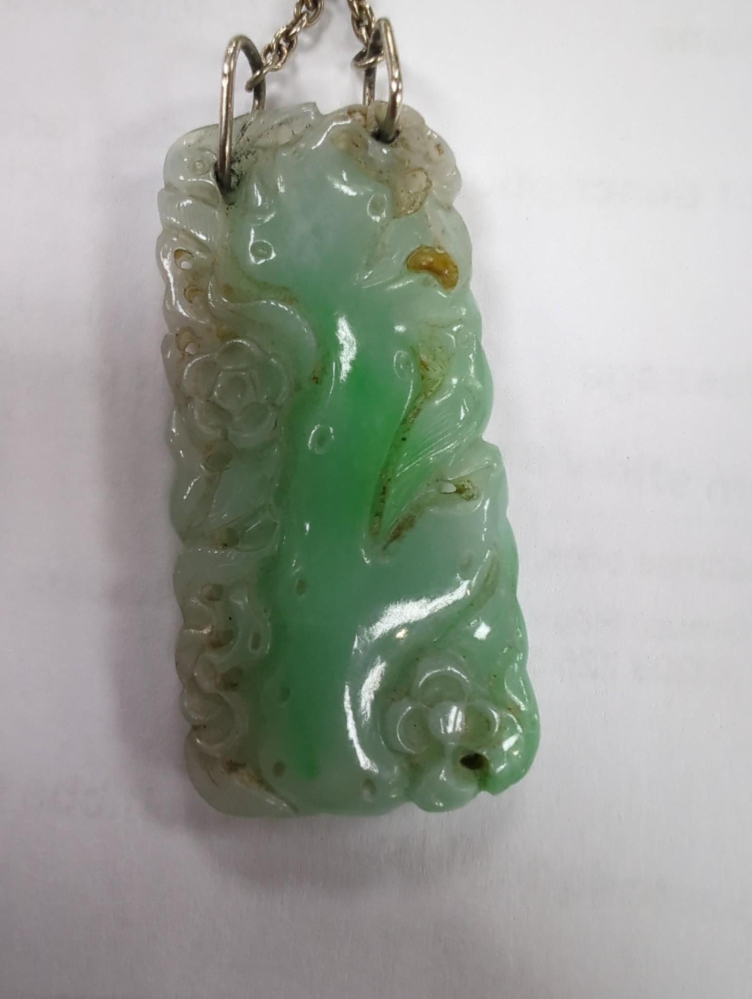 Two carved jade pendants, largest 47mm on a white metal chain.